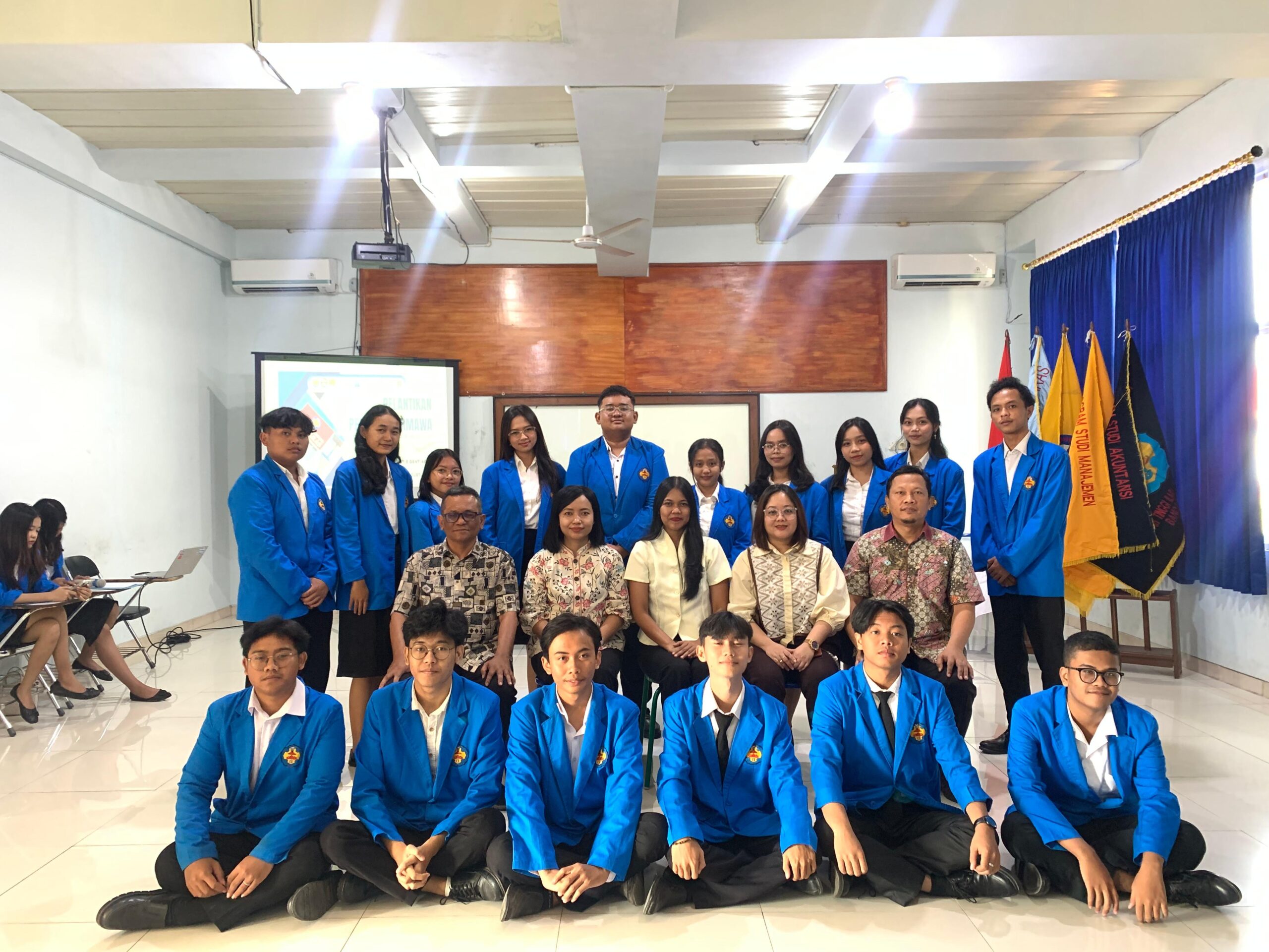 Pengurus Himpunan Mahasiswa Program Studi Manajemen berjas almamater biru berfoto bersama dosen seusai pelantikan