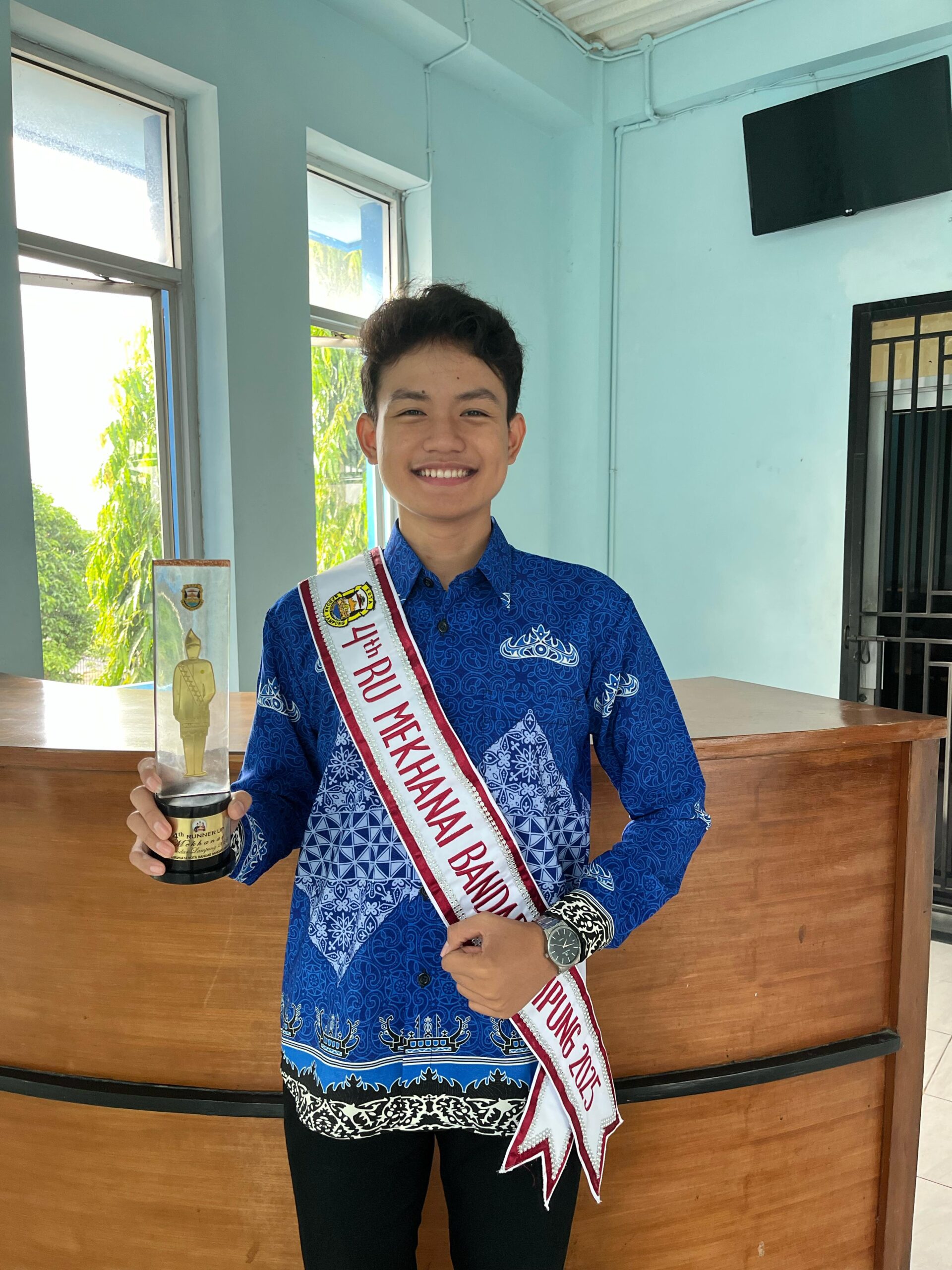 Mahasiswa Gentiaras mengenakan selempang 4th Runner Up Mekhanai Bandar Lampung sambil memegang trofi kemenangan