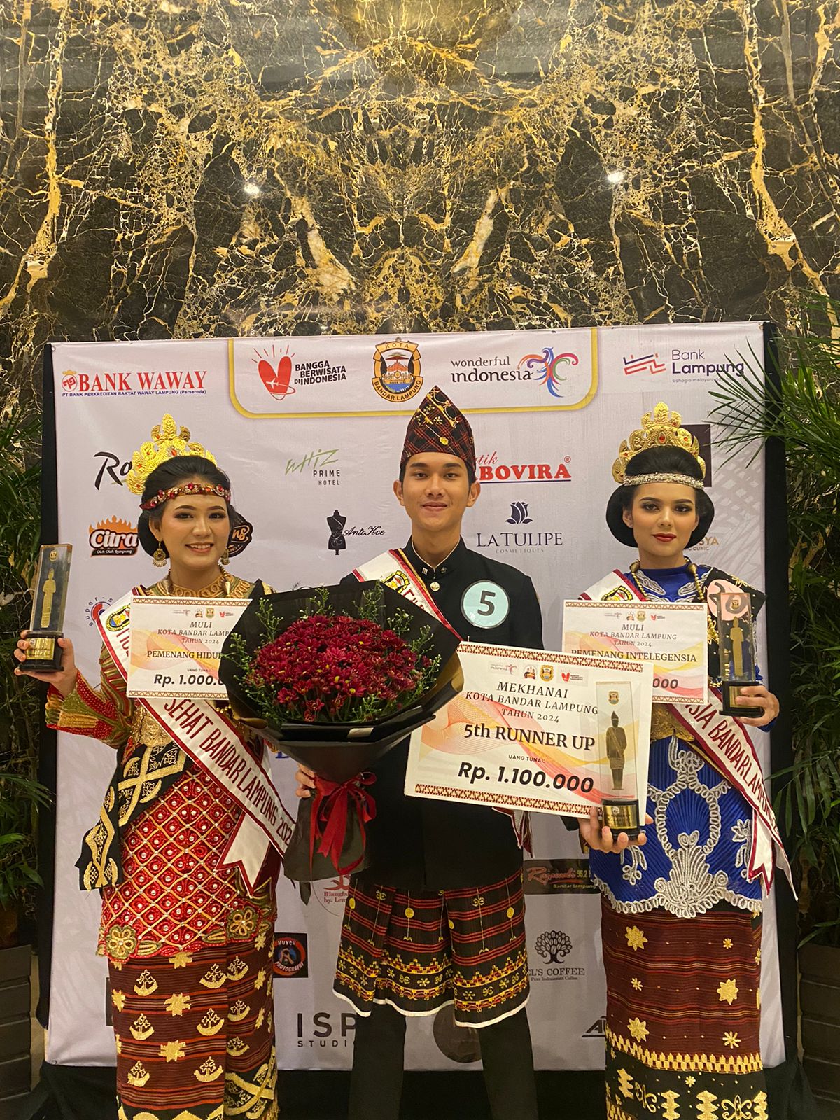 Tiga mahasiswa Gentiaras berbusana adat Lampung berdiri bersama memegang piagam kemenangan ajang Muli Mekhanai Kota Bandar Lampung